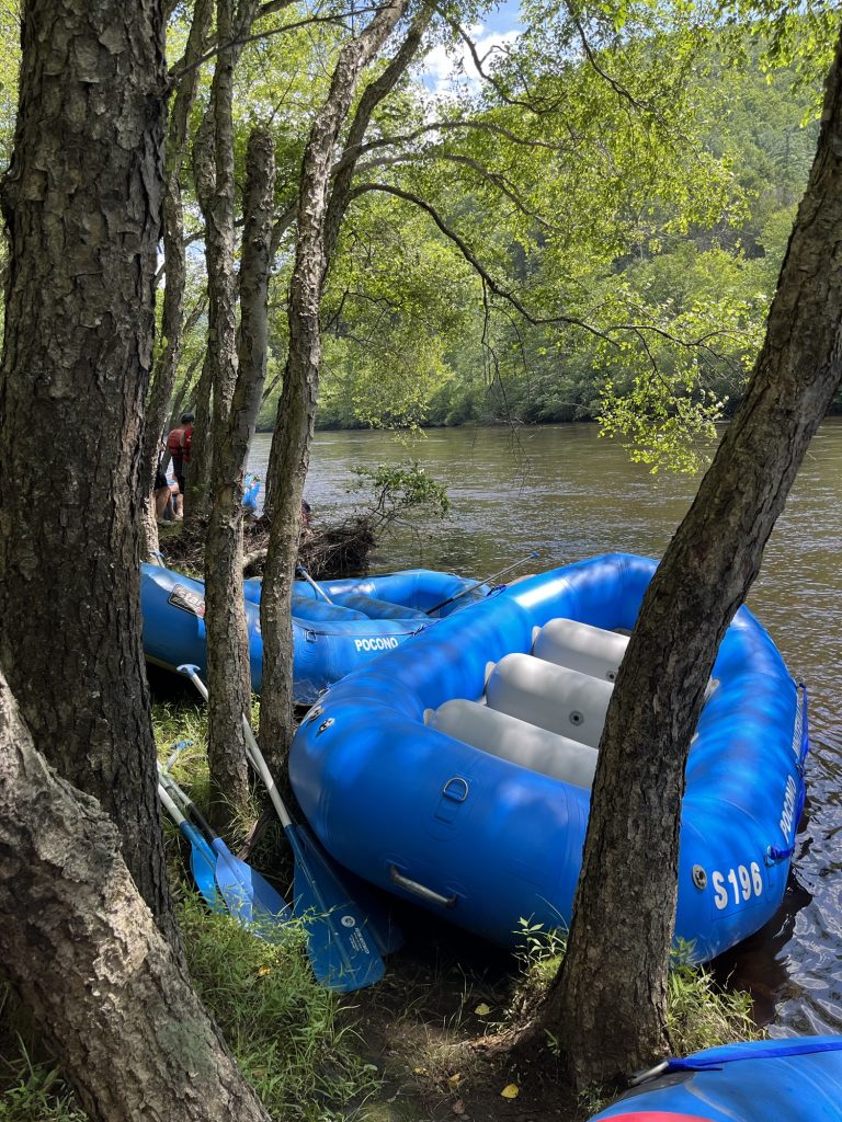 Blue rafts lined up along the Lehigh River surrounded by lush forest in Pennsylvania.