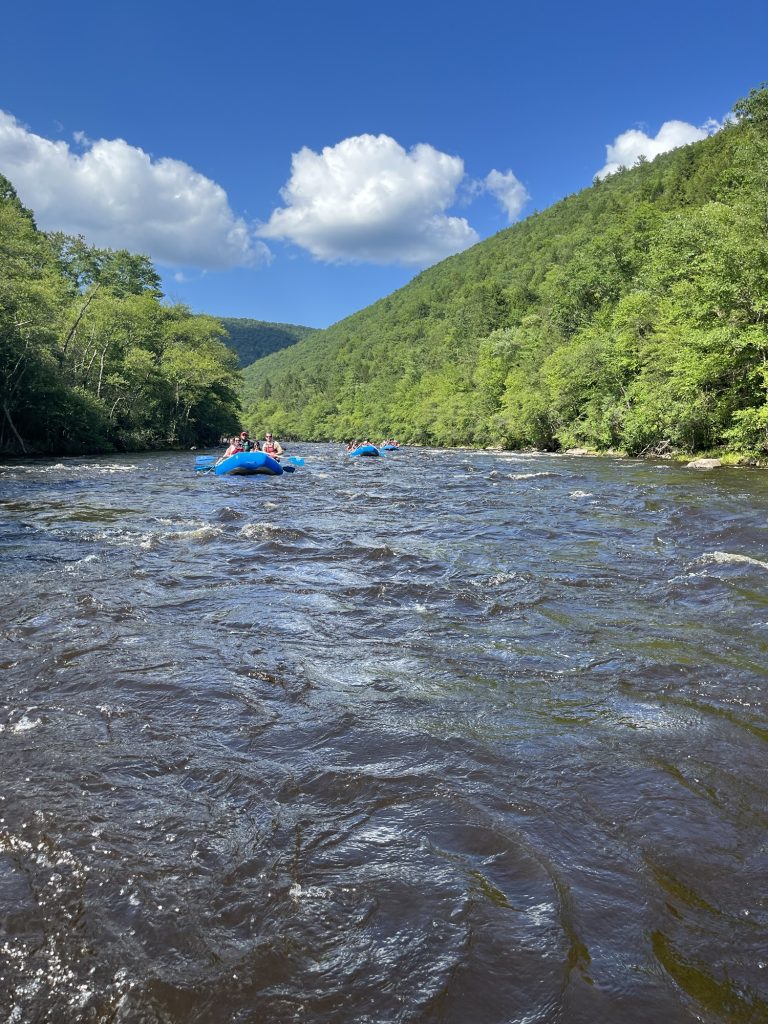Blue rafting boats floating down the Lehigh River during a Pocono Whitewater rafting trip in Pennsylvania.