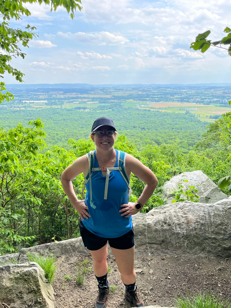 Hiker standing at a scenic Appalachian Trail overlook with views of Pennsylvania farmland and forests below
